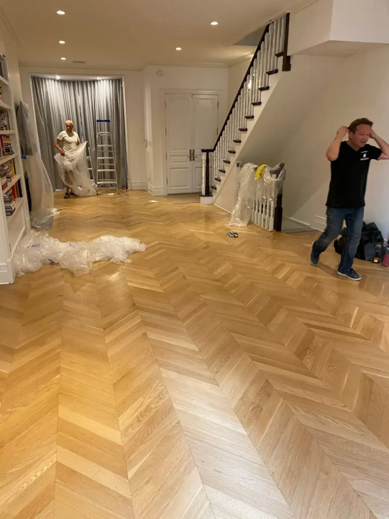 5th Avenue Brooklyn brownstone parlor with chevron flooring and detailed staircase finishes