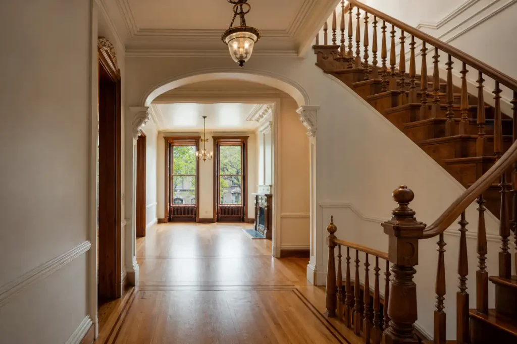 Restored Carroll Gardens brownstone stair hall and parlor with original woodwork, plaster molding, and refinished floors