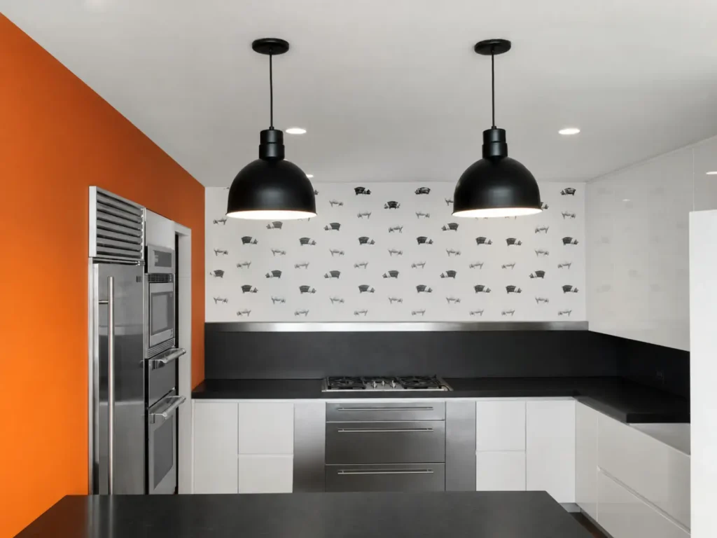Completed East 17th Street Manhattan loft kitchen with white cabinetry, dark counters, and black pendant lights