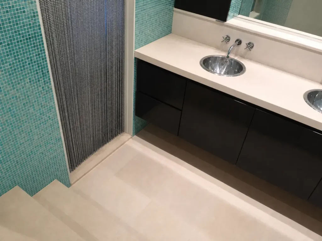 Turquoise mosaic-tile bathroom with black floating vanity in an East 17th Street Manhattan loft