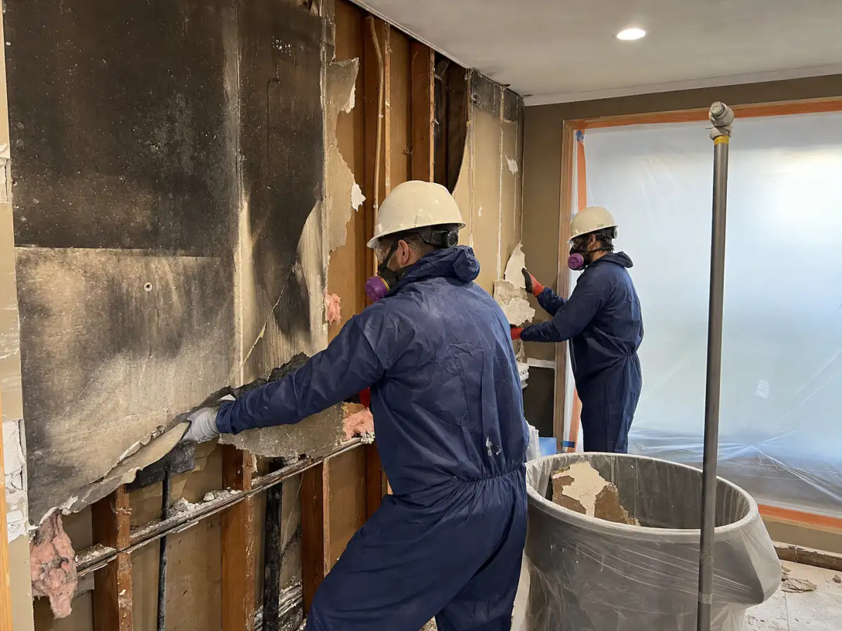 Restoration crew safely removing smoke-damaged drywall during controlled demolition