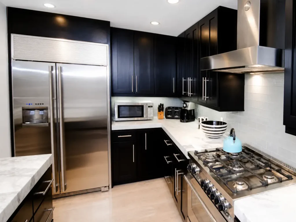 Completed guest house kitchen with dark cabinetry and stainless steel appliances in Hampton Bay