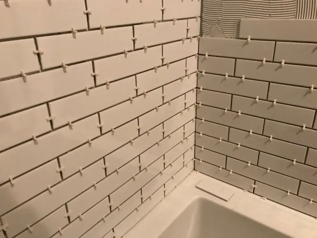 White subway tile installation with dark grout in a Long Island City bathroom