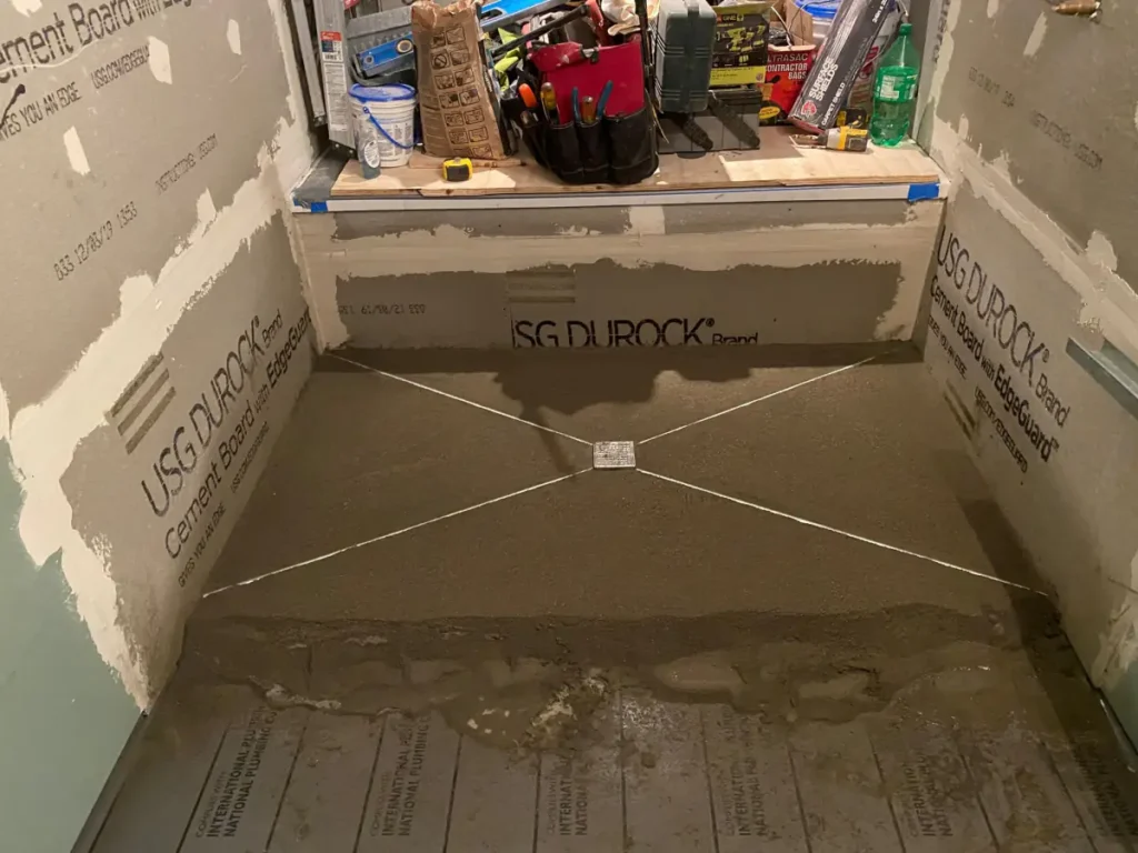 New shower base pitched toward a center drain before waterproofing and tile