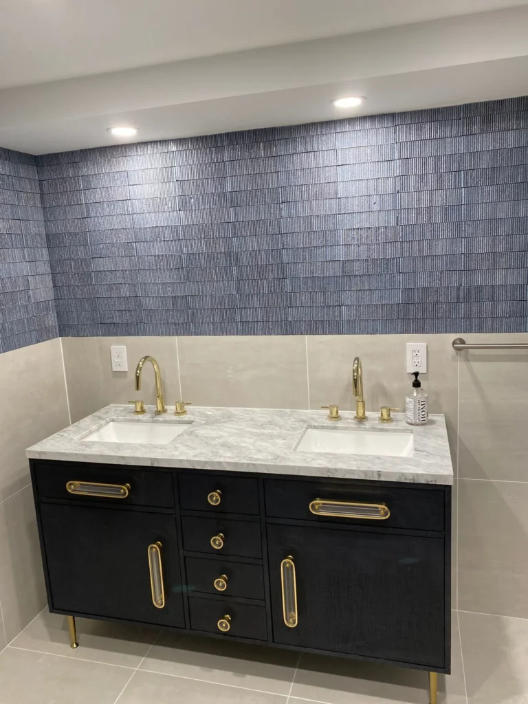 Black double vanity with pale stone top, two undermount sinks, brass faucets and hardware, and deep-blue textured tile in a Park Slope bathroom